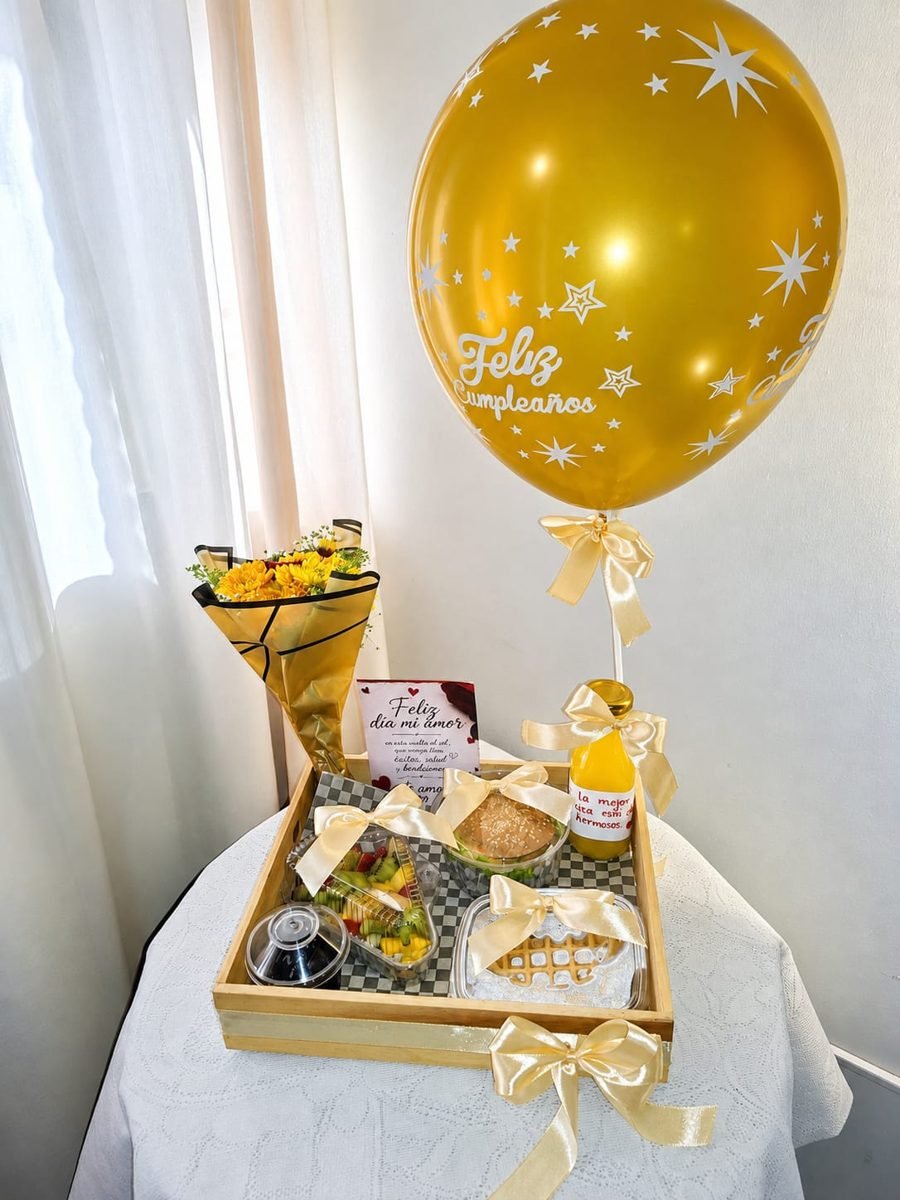 Bandeja dorada con flores, sándwich, jugo, waffle y globo de cumpleaños